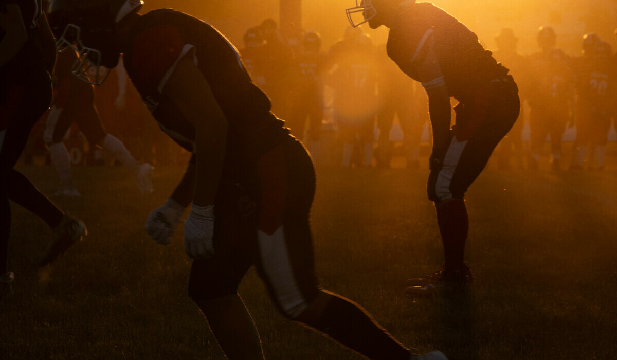 A foggy football field with silhouettes of football players